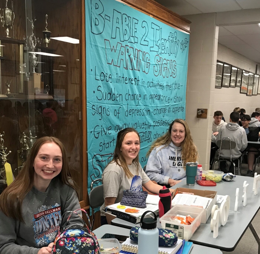 people at a lunch room table with a blue banner